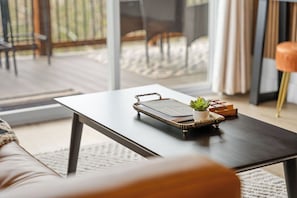 Un salon moderne avec une table basse en bois foncé, un livre, une petite plante et un plateau décoratif.