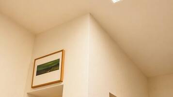 A room with a skylight, framed artwork on the walls, and a refrigerator.