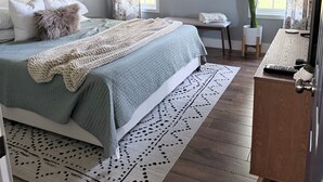Ein Schlafzimmer mit Bett, Nachttischen, einem Schminktisch, einem Deckenventilator und einem Fenster mit Vorhängen.