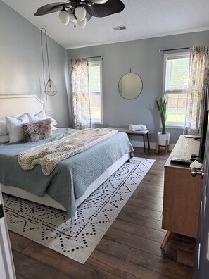 A bedroom with a bed, bedside tables, a dresser, a ceiling fan, and a window with curtains. - Stylish 3-bedroom house, 15 minutes from the beach! (Wilmington)