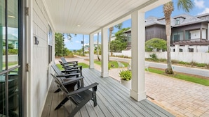 A covered outdoor area with a wooden deck, outdoor seating, and a view of neighboring houses. - Charming Inlet Beach Compound | Pool + Walk to Rosemary Beach (Inlet Beach)