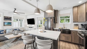 A modern kitchen with a large island, bar stools, a refrigerator, and a stove. - Charming Inlet Beach Compound | Pool + Walk to Rosemary Beach (Inlet Beach)