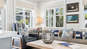 A living room with a sofa, a coffee table, a lamp, and framed artwork on the wall. - Charming Inlet Beach Compound | Pool + Walk to Rosemary Beach (Inlet Beach)