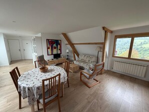 A spacious loft with a dining area, a sofa, a TV, and a large window with a view. - La Posette - LE CHATELARD (LE CHATELARD)