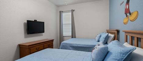 Un dormitorio con dos camas, ventilador de techo, televisión y ventana con persianas.