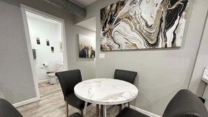 A room with a round marble table, black leather chairs, and a large abstract painting on the wall. - 2BR.KingBed.NearStadiums.BalconyAccess.NoStairs (Arlington)