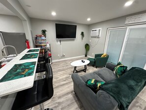 Una sala de estar moderna con un sofá gris, una mesita redonda y un televisor montado en la pared.