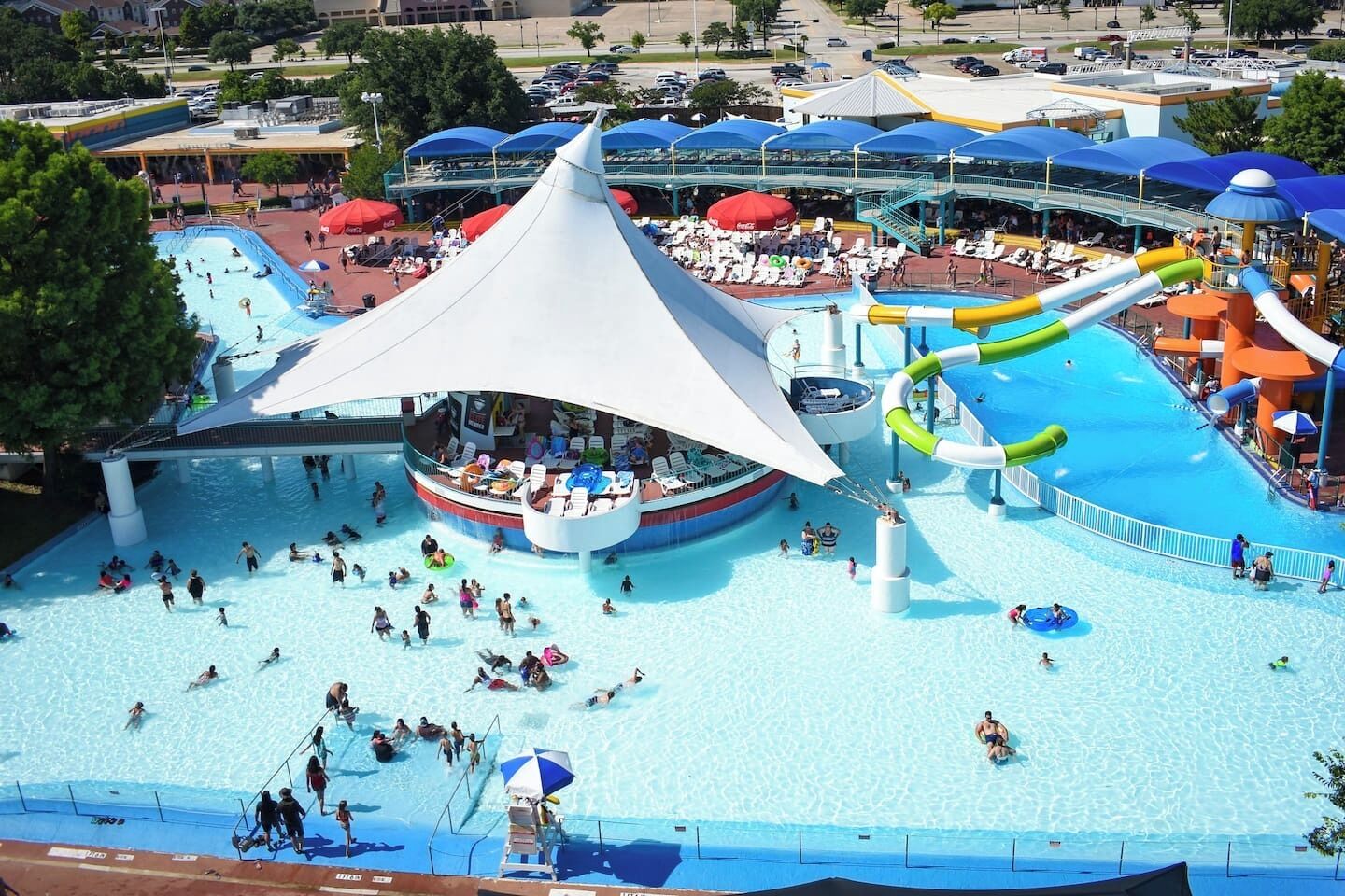 A water park with a central pool, multiple slides, and a covered area with seating.