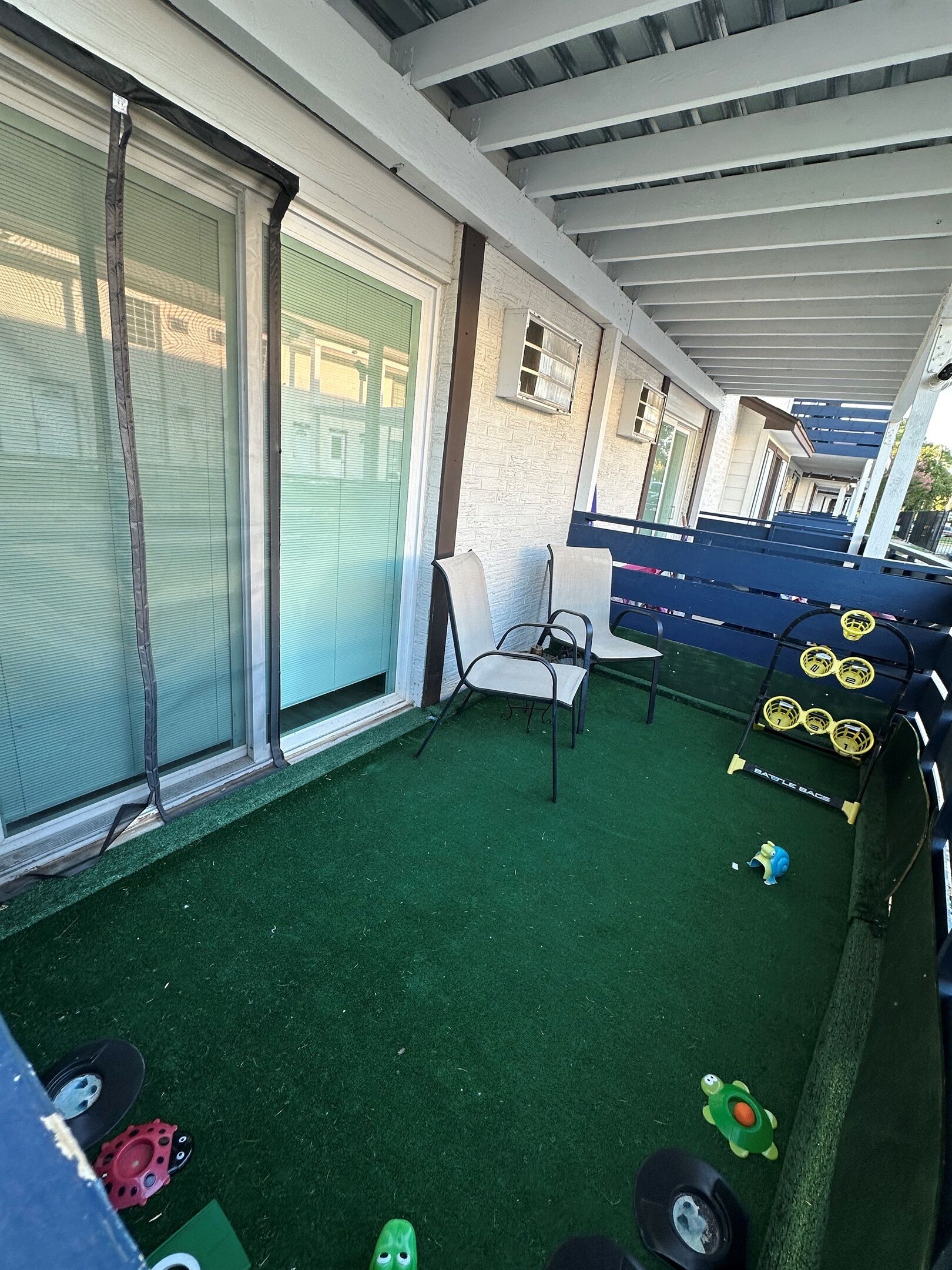 A covered outdoor area with artificial turf, seating, and exercise equipment.