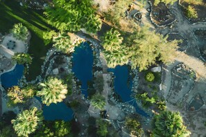 An aerial view of a landscaped area with multiple ponds, pathways, and scattered trees. - Sunset Overlook at The Bubbling Wells Oasis (Desert Hot Springs)