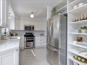 A modern kitchen with white cabinets, stainless steel appliances, and a built-in oven.