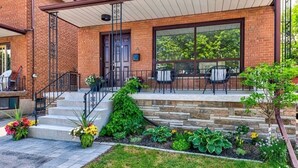 Un bâtiment en briques doté d’un patio couvert, d’un espace extérieur aménagé pour s’asseoir et d’un jardin bien entretenu.