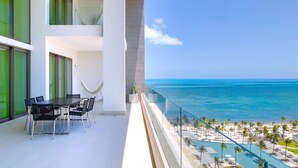 A balcony with a view of the ocean and a pool area.
