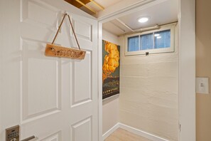 Una puerta blanca con un letrero que dice 'WELCOME', un cartel de una flor y una ventana con vistas.