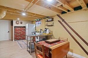 A compact kitchen with a refrigerator, sink, and a dining table with chairs. - The  Yellowbike  Den (Livingston)