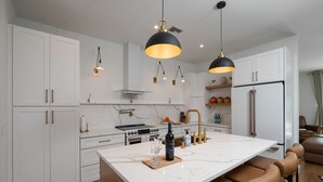 A modern kitchen with white cabinetry, a marble island, and pendant lighting.