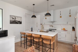 A modern kitchen with a central island, pendant lights, and a dining area with bar stools. - Spacious retreat w/private pool & screened patio (Vero Beach)