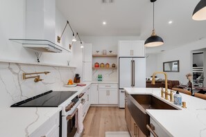 A modern kitchen with a black stove, white cabinets, and a wooden countertop. - Spacious retreat w/private pool & screened patio (Vero Beach)