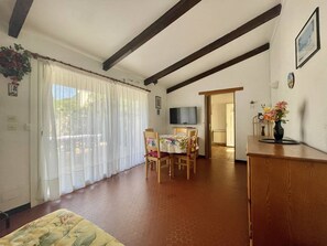 A room with a dining table, chairs, a television, a wooden cabinet, and a door leading to another room. - CAP D'ADGDE - La Pinède / Réf 141 (CAP D'AGDE)