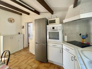 A kitchen with a refrigerator, oven, microwave, and a dining table with chairs. - CAP D'ADGDE - La Pinède / Réf 141 (CAP D'AGDE)