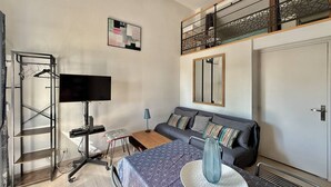 Una camera moderna con divano, televisione, scrivania e balcone con ringhiera.