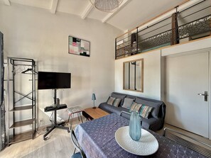 A modern room with a sofa, a TV, a desk, and a balcony with a railing. - CAP D'AGDE - Plage Richelieu / Réf 418 (CA P D'AGDE)