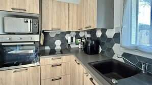 Una cucina moderna con mobili in legno, un forno a microonde, un forno, una macchina per il caffè e una finestra con vista.