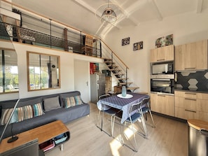 A modern apartment with a dining area, kitchen, and a staircase leading to an upper level. - CAP D'AGDE - Plage Richelieu / Réf 418 (CA P D'AGDE)