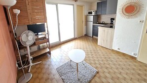 A compact kitchen with a microwave, refrigerator, and a small dining table. - CAP D'AGDE - Plage du Môle / Réf 230 (CAP D'AGDE)