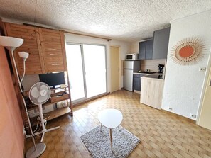 A compact kitchen with a microwave, refrigerator, and a small dining table. - CAP D'AGDE - Plage du Môle / Réf 230 (CAP D'AGDE)