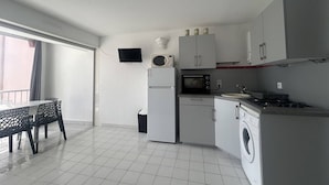 Een functionele keuken met een koelkast, magnetron, fornuis en wasmachine.