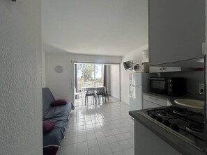 A compact living space with a kitchenette, a dining area with a table and chairs, and a sofa with a cushion. - CAP D'AGDE - Plage Richelieu / Réf 276 (CAP D'AGDE)