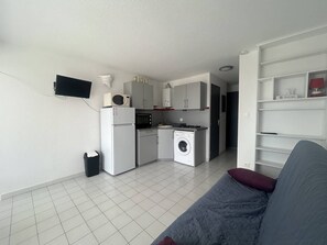 A compact living space with a kitchenette, a washing machine, a sofa, and a TV mounted on the wall. - CAP D'AGDE - Plage Richelieu / Réf 276 (CAP D'AGDE)