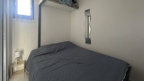 Een slaapkamer met een bed, een raam, een lamp en een wandplank.