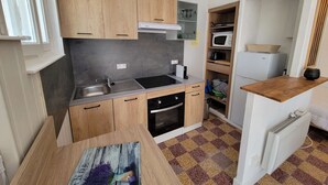 A compact kitchen with wooden cabinets, a built-in microwave, and a small oven. - Lovely studio fo 2 or 3 people, only 100m away from the beach of Portiragnes plage (PORTIRAGNES)