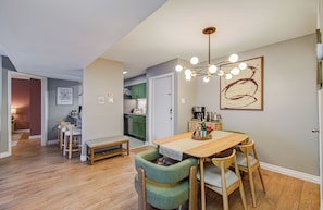 A dining area with a wooden table, green upholstered chairs, a bench, and a pendant light.