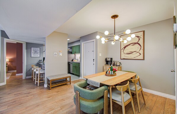 A dining area with a wooden table, green upholstered chairs, a bench, and a pendant light.