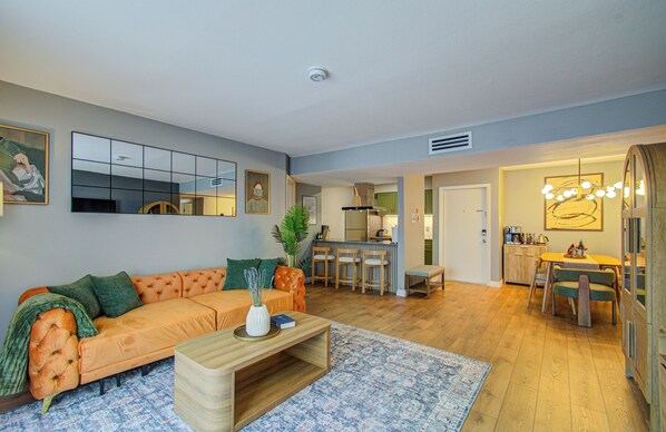 A living room with a sofa, coffee table, and a dining area with chairs and a table.