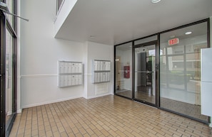 A hallway with lockers, an exit sign, and a tiled floor.
