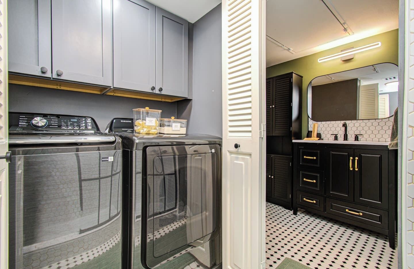 A laundry room with two washing machines, a dryer, and a cabinet with storage containers.