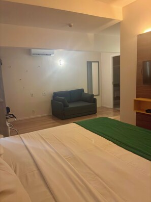 A hotel room with a bed, a sofa, a green throw, a mirror, and a wardrobe. - MAORI MANTIQUEIRA HOTEL (Cruzeiro)