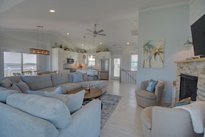 A spacious living area with a large sofa, a coffee table, and a fireplace. - Soundfront 3BR home with pool, hot tub, dock, and ocean access. (North Topsail Beach)