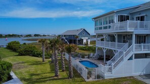 A multi-story beachfront property with a pool, outdoor seating, and a view of the sea. - Soundfront 3BR home with pool, hot tub, dock, and ocean access. (North Topsail Beach)