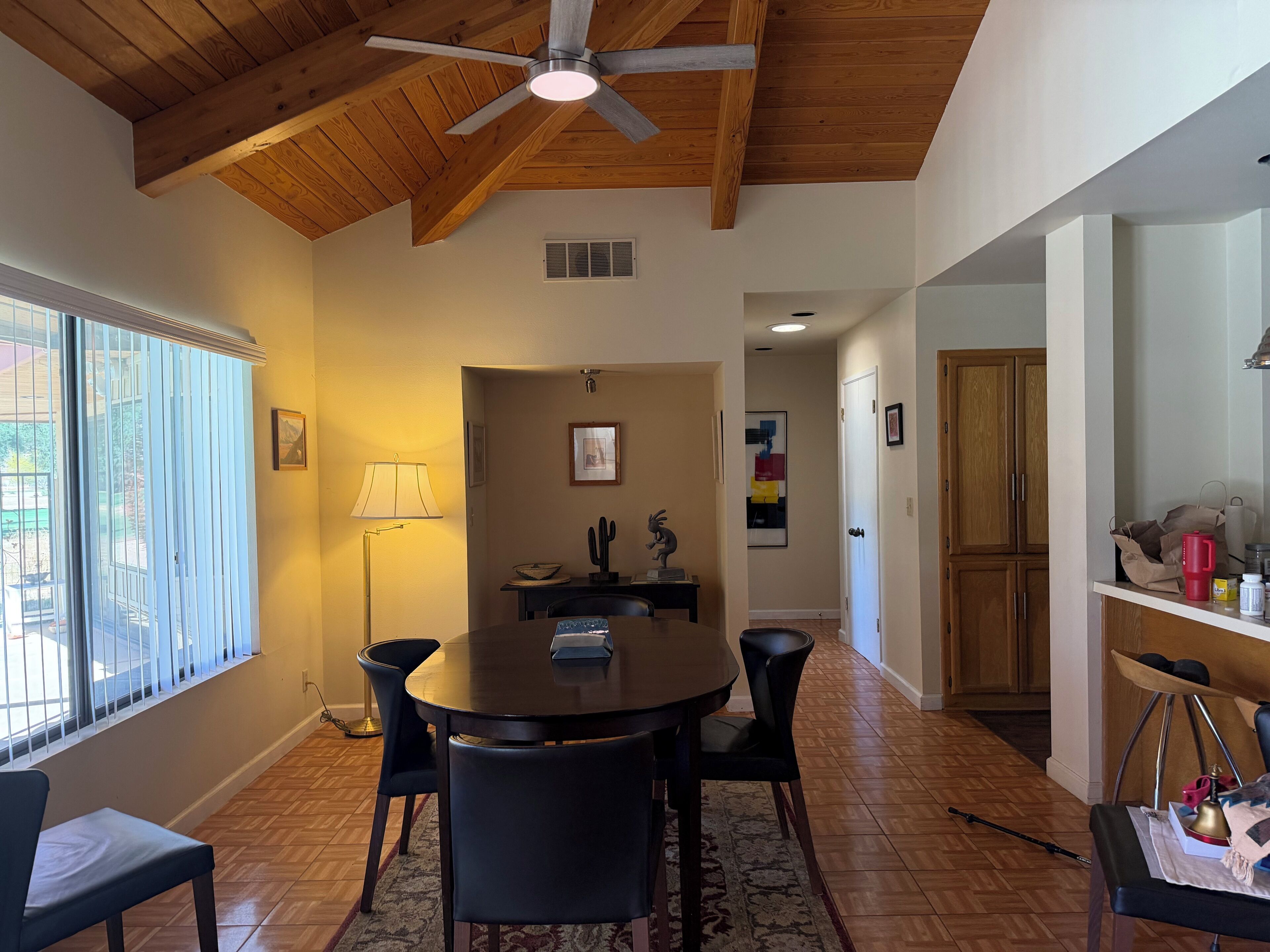 A dining area with a round table, chairs, a ceiling fan, and a lamp.
