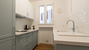 Eine Küche mit hellblauen Schränken, einer weißen Arbeitsplatte, einem Fenster und einem Spülbecken.