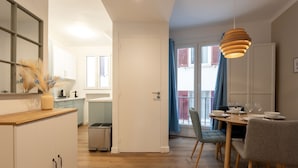 Eine moderne Küche mit weißen Schränken, einer Holzausziehtischplatte und einem Essbereich mit Tisch für vier Personen.