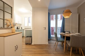 Eine moderne Küche mit weißen Schränken, einer Holzausziehtischplatte und einem Essbereich mit Tisch für vier Personen.