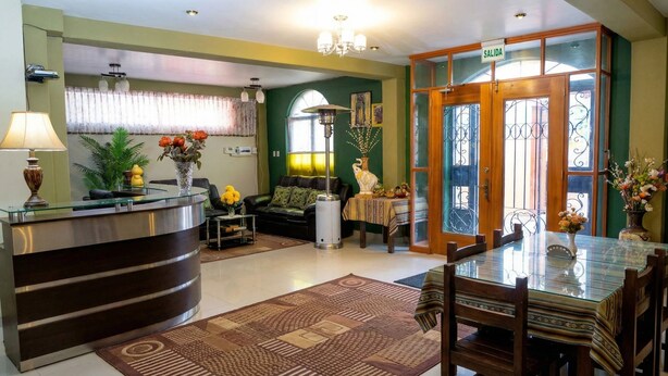 A reception area with a desk, chairs, a sofa, a dining table, and a chandelier.