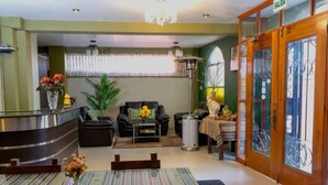 A reception area with a reception desk, a sofa, a coffee table, and a dining table with chairs.