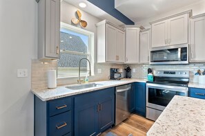 A modern kitchen with white cabinets, a stainless steel dishwasher, a built-in oven, and a microwave. - Shore Thing | Steps to Pool | Hot Tub + Pool Table (Hollister)